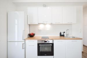cocina con armarios blancos y nevera blanca en New Family Apartments with private parking near Zadar en Murvica