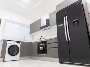 a kitchen with a black refrigerator and a washing machine at Greenfield’s Apartment in Amrahia