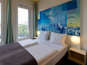 - une chambre dotée d'un lit king-size et d'une fresque murale décorative dans l'établissement B&B Hotel Fulda-City, à Fulde