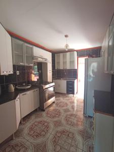 a kitchen with white cabinets and a tile floor at Casa Bela vista São José in Piranhas