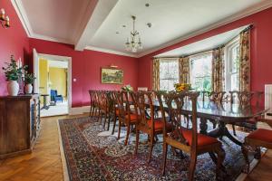 a dining room with red walls and a table and chairs at Saham Grove Hall by Group Retreats in West Bradenham