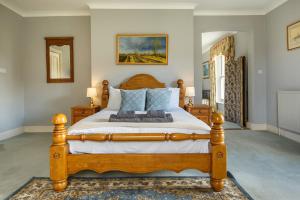 a bedroom with a large wooden bed with blue pillows at Saham Grove Hall by Group Retreats in West Bradenham