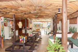 un restaurante con mesas de madera, sofás y sillas en Popoyo Surf Resort, en Arugam Bay