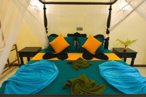 a bedroom with a bed with blue sheets and yellow pillows at Monkey Island Hotel in Hikkaduwa