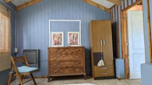 a bedroom with a dresser and a mirror and a chair at Cabaña Rio Sur in Junín de los Andes