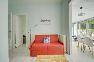 a red couch in a living room with a table at Jolie maison au Bouscat avec jardin in Le Bouscat