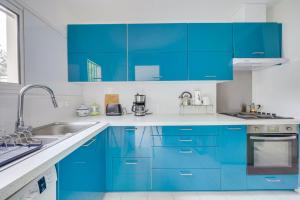 une cuisine bleue avec des comptoirs blancs et des armoires bleues dans l'établissement Jolie maison au Bouscat avec jardin, à Le Bouscat