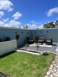 un patio con bancos y césped frente a una pared en Playa y Campo Balcony Studio en Isabela