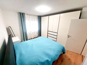a small bedroom with a blue bed and a window at Haus am See in Heddesheim