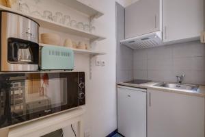 a small kitchen with a microwave and a sink at Charming hypercentre apartment Bordeaux in Bordeaux