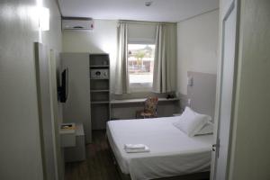 Un pequeño dormitorio con una cama blanca y una ventana en DE STEFANI HOTEL, en Portão