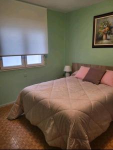 Un dormitorio con una cama grande con almohadas rosas y una ventana en San Lorenzo 11, en Gijón