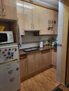 cocina con armarios de madera y microondas blanco en San Lorenzo 11, en Gijón