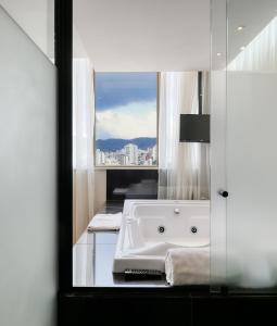 ein Bad mit einer Badewanne und einem Fenster in der Unterkunft Mercure Belo Horizonte Lourdes in Belo Horizonte