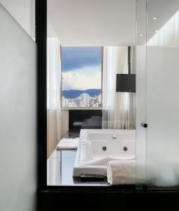 a bathroom with a bath tub and a window at Mercure Belo Horizonte Lourdes in Belo Horizonte