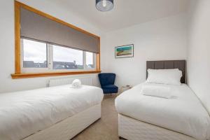 een slaapkamer met 2 bedden en een blauwe stoel bij Greentiles - Spacious House - Extensive Garden - Convenient Location in St Andrews
