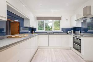 een grote keuken met witte kasten en een wastafel bij Greentiles - Spacious House - Extensive Garden - Convenient Location in St Andrews
