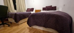 a bedroom with two beds with purple comforters at 4-Bed Apartment in Central London in London