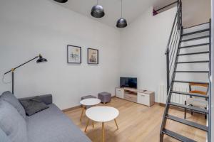 uma sala de estar com um sofá cinzento e uma escada em Charmante petite maison de ville Bordeaux, Talence em Talence