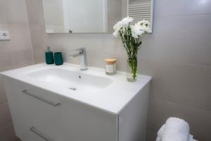 un baño con lavabo blanco con un jarrón de flores en SingularStays Picaña, en Picaña