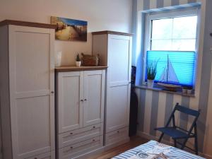 a bedroom with white cabinets and a window and a chair at Doppelhaushälfte Dock No 7 0 in Zirchow in Zirchow
