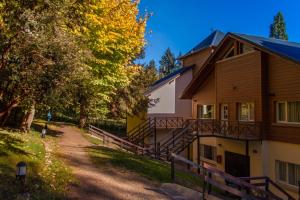 a house with a staircase next to a dirt road at Huinid Bustillo Cabañas in San Carlos de Bariloche