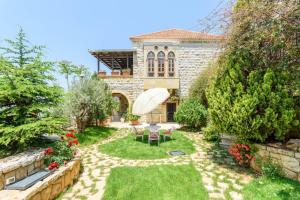a house with a garden with chairs and an umbrella at Authentic Villa with Pool and Garden in Beit Chabeb 