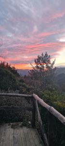 um deque de madeira com um pôr-do-sol ao fundo em Apartamentos Rurales El Bosque de las Viñas em Boal