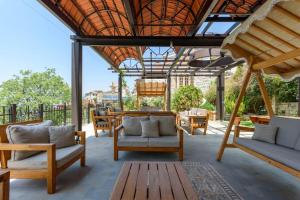 um pátio com cadeiras e mesas e um telhado de madeira em Authentic Villa with Pool and Garden in Beit Chabeb 