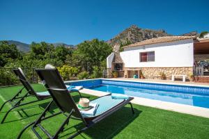 a villa with a swimming pool and two lawn chairs at EL MIRADOR in Jaén