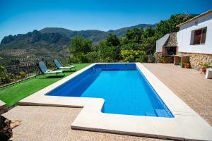a swimming pool with two chairs and a house at EL MIRADOR in Jaén