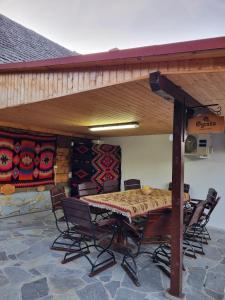 a patio with a table and chairs under a roof at POIANA MARAMURESEANA in Călimăneşti