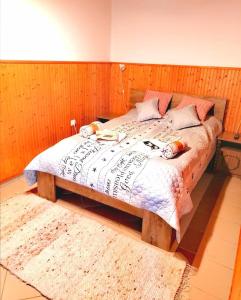 a bedroom with a large bed with a wooden wall at Flower Tisza Vendégház in Tiszafüred