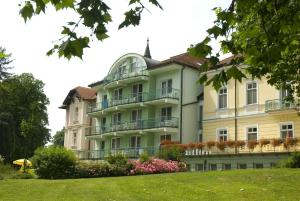 a large building with flowers in front of it at Hotel Spa Hévíz in Hévíz