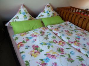 a bed with a floral comforter and pillows at Ferienhaus mit Kamin , Terrasse und Aussensauna in Pöhla