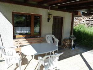 einen weißen Tisch und Stühle auf einer Terrasse in der Unterkunft Ferienhaus mit Kamin , Terrasse und Aussensauna in Pöhla