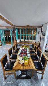 una larga mesa de madera con sillas y comida. en Vừng Homestay - Mộc Châu, en Mộc Châu