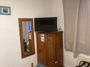 a television on top of a wooden cabinet with a mirror at Alba b & b in Inverness