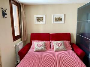 Una cama roja con dos almohadas encima. en Alpine Studio with Garage, en Breuil 14 fotos más