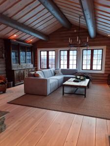 uma sala de estar com um sofá e uma mesa em Stor og flott hytte med fantastisk utsikt em Geilo