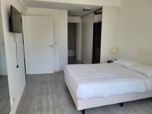 1 dormitorio con 1 cama blanca y TV en APART PARAGUAY Y FITZ ROY 3 en Buenos Aires
