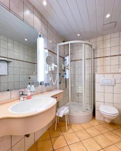 ein Badezimmer mit Dusche, Waschbecken und Toilette in der Unterkunft AhrPart Hotel Central in Bad Neuenahr-Ahrweiler