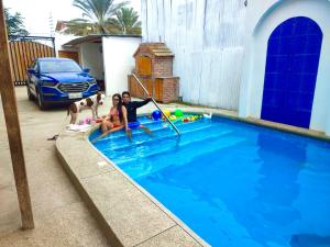 a man and two girls sitting in a swimming pool at Casa de Hamacas in Ballenita