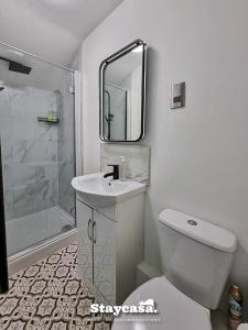 a bathroom with a toilet and a sink and a mirror at Stylish 10 Bedrm House, Fast Wifi, Free Parking in Manchester