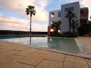 a swimming pool in front of a building with palm trees at Apartamento Arade Mar in Portimão