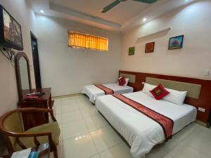 1 dormitorio con 2 camas, escritorio y ventana en ANH ĐÀO HOTEL LẠNG SƠN, en Lạng Sơn