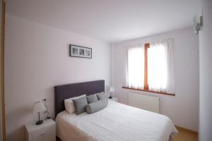 a white bedroom with a bed and two windows at 1. APT cerca a pistas de esquí y la Vall d'Incles in Soldeu