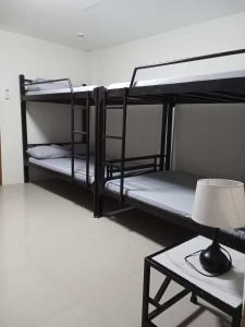 2 Etagenbetten in einem Zimmer mit einer Lampe und einem Tisch in der Unterkunft RICHVILLE LITTLE BORACAY GUEST HOUSE in Calatagan