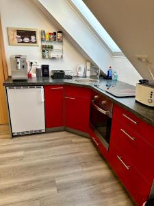 eine Küche mit roten Schränken und einem weißen Gerät in der Unterkunft Gäste-Appartement-Kirsammer in Eningen unter Achalm