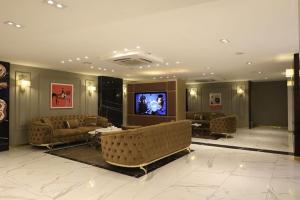 a living room with couches and a flat screen tv at The Capital Heart Hotel in Baghdād